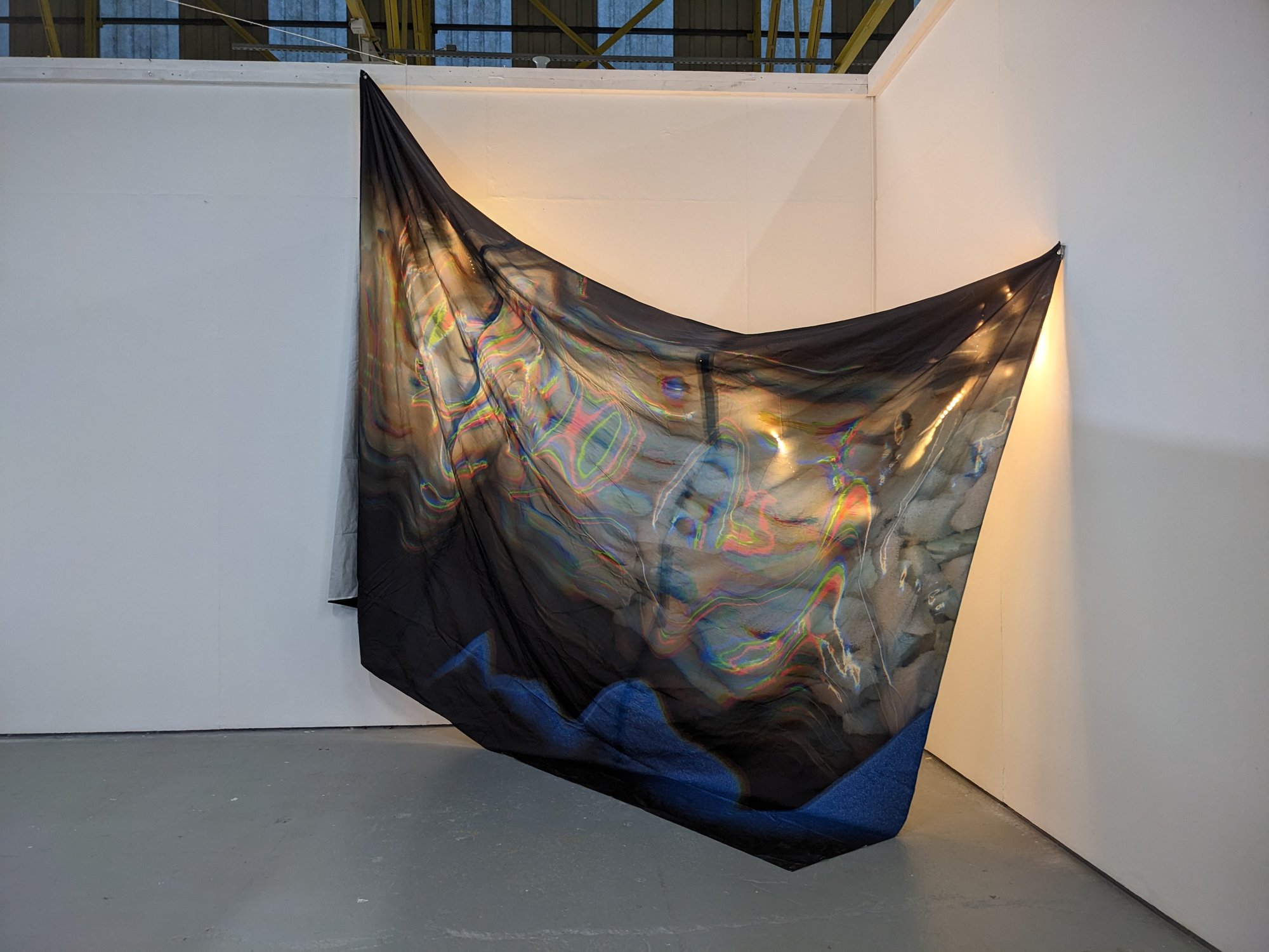 Large fabric textiles piece hanging in the corner of The Royal Standard with lights behind